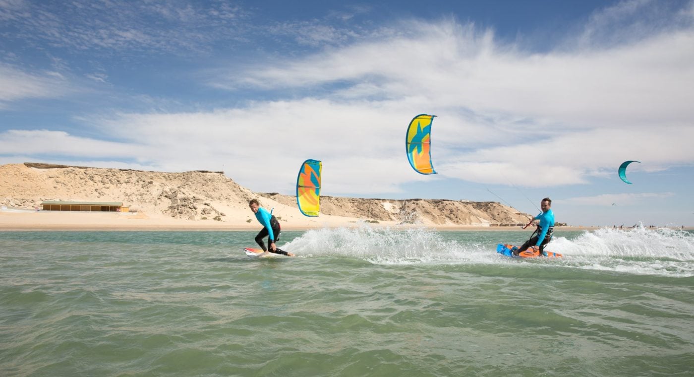 Kitesurfers riding on Dakhla Lagoon with the desert cliffs behind