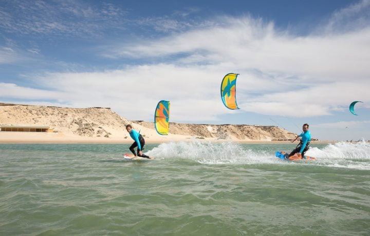 Kitesurfers riding on Dakhla Lagoon with the desert cliffs behind
